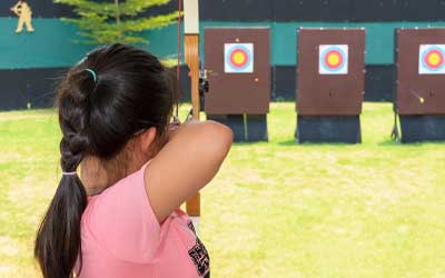 girl doing archery at ymca camp