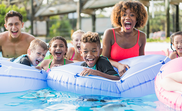 kids play in tubes in pool while counselors smile
